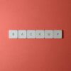 Free Close-up of keyboard keys spelling 'BACKUP' placed on a coral-colored surface. Stock Photo