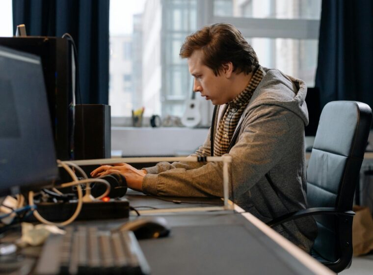 Free A concentrated professional working at a computer in a modern office setting. Stock Photo